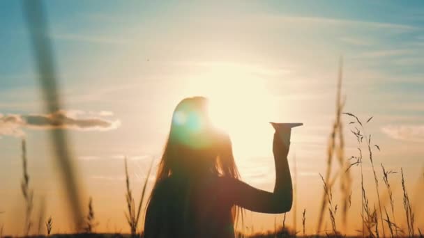 Boldog kis lány játszik egy papírrepülő szabadban során naplemente. Sziluett naplementekor. Koncepció nagy álma.