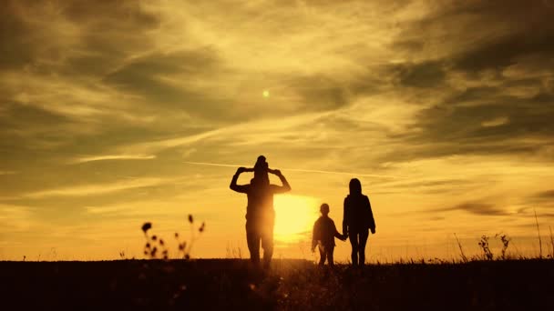 Silhouettes of father, mother and children hiking. Baby sits on ...