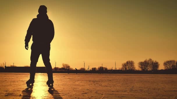 Silhouette of a man skating on ice on lake against to winter sun.