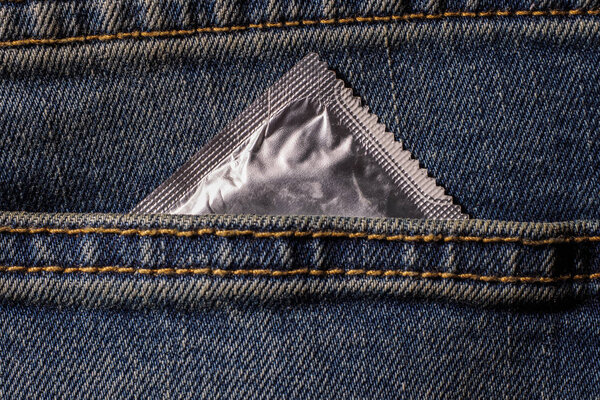 condom in blue jeans pocket,Protect yourself Use a condom.a woman holding a condom ,ready for use