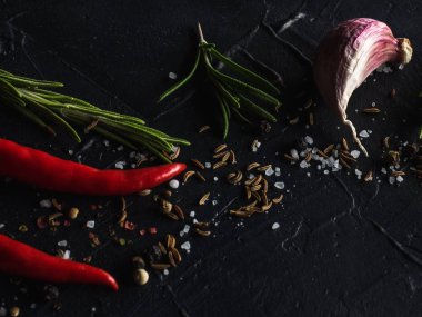 Kırmızı sıcak biber biber, sarımsak ve biberiye deniz tuzu ve siyah arka plan üzerinde renkli biber ile