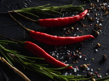 Kırmızı sıcak biber biber, sarımsak ve biberiye deniz tuzu ve siyah arka plan üzerinde renkli biber ile