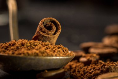 vintage bir çekilmiş kahve kaşığı tarçın sopayla. baharat ile kahve. Gıda arka plan üzerinde koyu taş tablo. Makro yakın çekim yansıma.
