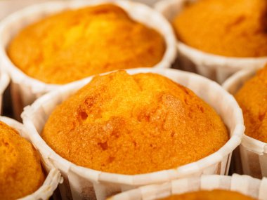 Sabahları kahvaltıda taze pişmiş tarçınlı mini kekler. Ahşap bir zemin üzerine yeşil kağıt tutucu.