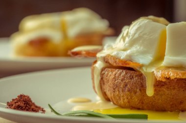Kahvaltı Yumurta Benedict - tost İngilizce muffins, pastırma, jambon, haşlanmış yumurta, otlar ve lezzetli tereyağı hollandaise sosu olduğunu. 