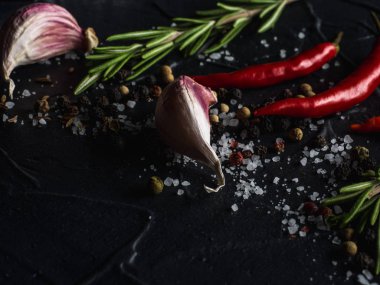 Kırmızı sıcak biber biber, sarımsak ve biberiye deniz tuzu ve siyah arka plan üzerinde renkli biber ile