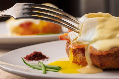 Kahvaltı Yumurta Benedict - tost İngilizce muffins, pastırma, jambon, haşlanmış yumurta, otlar ve lezzetli tereyağı hollandaise sos var. Yakın çekim resmin. Sığ derinlik-in tarla.