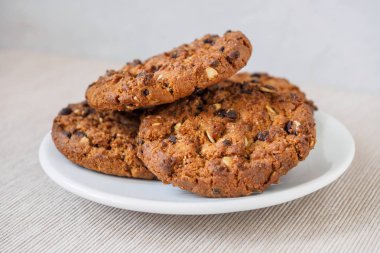 Beyaz zemin üzerine çikolatalı kurabiye. Çikolatalı kurabiye kahverengi peçete üzerinde yığılmış. Sembolik görüntü metin için yer ile. Fırından yeni çıkmış. Lezzetli bir aperatif için kavram. Şekerli tatlı. Seçici odak. Yakın çekim.