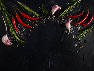 Kırmızı sıcak biber biber, sarımsak ve biberiye deniz tuzu ve siyah arka plan üzerinde renkli biber ile