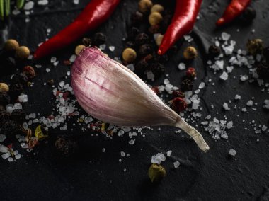 Kırmızı sıcak biber biber, sarımsak ve biberiye deniz tuzu ve siyah arka plan üzerinde renkli biber ile