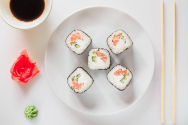 Rulo suşi bir plaka üzerinde suşi roll bir tablet üzerinde tablo restoran / yemek çubukları kullanarak suşi roll yeme, beyaz arka plan, suşi roll ve çubuklarla el. Japon yemekleri. 