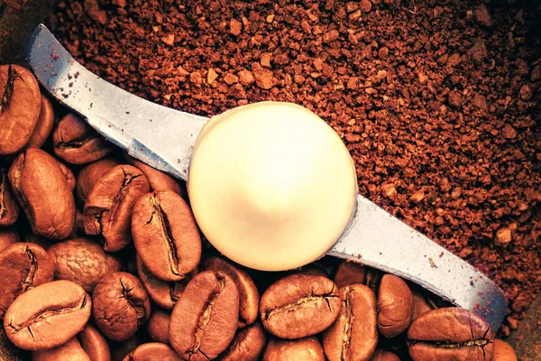 Macro photo of freshly ground coffee in electric coffee grinder. In one half whole grains of coffee, and in the other half ground.