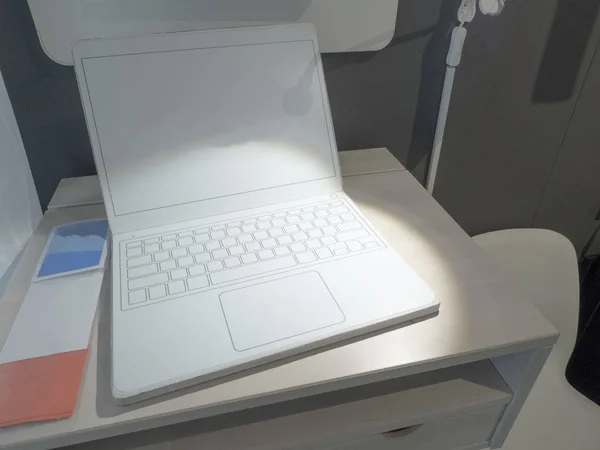 Front view of a modern laptop with a white screen and an empty white keyboard on a table.