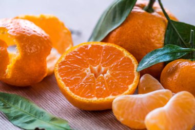 Olgun Mandarin soyulmuş meyve açın ve beyaz üzerinde yer ahşap mandalina meyve ve yaprakları odak arka planda Grup ile bak. Seçici odak. 