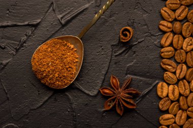 Kahve çekirdekleri çekilmiş kahve ve oryantal baharatlar, anason ve tarçın vintage bir kaşıkla. Karanlık bir taş zemin üzerinde. Üstten görünüm. Kopya alanı.