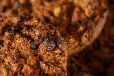 Rustik koyu siyah arka plan üzerine çikolatalı kurabiye. Çikolatalı kurabiye kahverengi peçete üzerinde yığılmış. Sembolik görüntü metin için yer ile. Fırından yeni çıkmış. Lezzetli bir aperatif için kavram. Şekerli tatlı. Seçici odak. Yakın çekim.