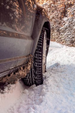 Lüks siyah crossover ormanda kış yolda mola yaptı. SUV. Araba lastikleri kış yolda karla kaplı. Sabah saat kar yağışı karlı sokak üzerinde araç.