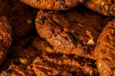 Rustik koyu siyah arka plan üzerine çikolatalı kurabiye. Çikolatalı kurabiye kahverengi peçete üzerinde yığılmış. Sembolik görüntü metin için yer ile. Fırından yeni çıkmış. Lezzetli bir aperatif için kavram. Şekerli tatlı. Seçici odak. Yakın çekim.