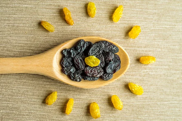 Blue Raisins in wooden spoon and anise on textile background on the kitchen.Composition in the form of sun or light bulb. symbol of idea or thought, raisins useful for brain. Healthy snack, Vega Food. Macro. Top view.