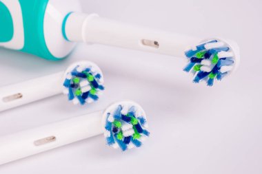 Beyaz arka plan üzerinde elektrikli diş fırçası ve diş hijyeni aksesuarları.