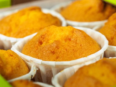 Sabahları kahvaltıda taze pişmiş tarçınlı mini kekler. Ahşap bir zemin üzerine yeşil kağıt tutucu.