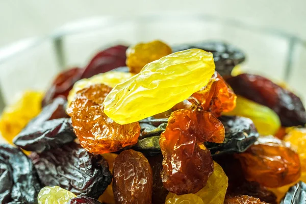 Assortment of Raisins, yellow, blue, black, golden raisin  in glass bowl and wooden spoon on kitchen. Healthy snack, dietary product for good life. copy space, Vega Food. Close-up image. Macro.