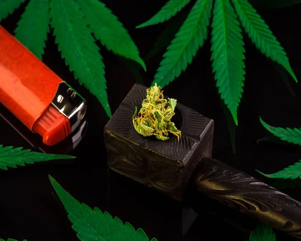 Mock up on wooden indian hipster smoking pipe, legal marijuana and red cigarette lighter. Cannabis friendly layout. Rasta background. Colorful image.