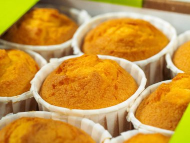 Sabahları kahvaltıda taze pişmiş tarçınlı mini kekler. Ahşap bir zemin üzerine yeşil kağıt tutucu.