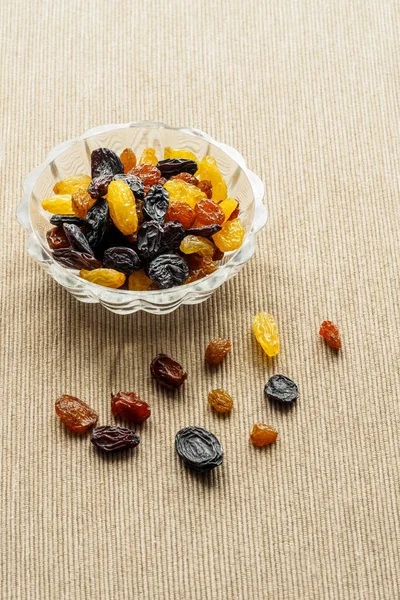 Assortment of Raisins, yellow, blue, black, golden raisin  in glass bowl on kitchen. Healthy snack, dietary product for good life. copy space, Vega Food.