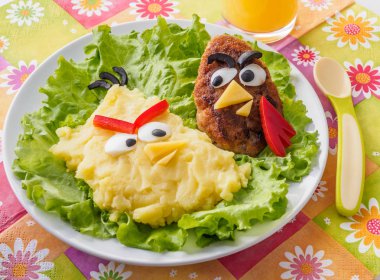 Çocuklar için yemek. patates püresi ve et katleta ile portakal taze kızgın kuşlar için stilize. parlak renkli çocuk masa örtüsü mutfak masasının üzerinde. Komik hayvanlar. Dikey düzen.
