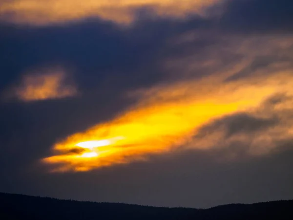 Sonnenuntergang bricht die Sonne durch dunkle Wolken und Wolken. Dramatische Szene — Stockfoto