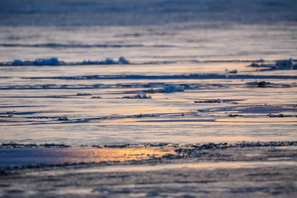 Ghiaccio primaverile si scioglie sul lago. riflesso del tramonto in tappetino scongelato — Foto Stock