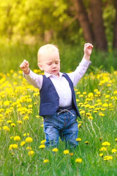 Маленький мальчик в модном стильном костюме на поляне цветущих криков — стоковое фото
