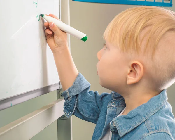 Criança desenha um menino em uma camisa jeans com um marcador em um b — Fotografia de Stock