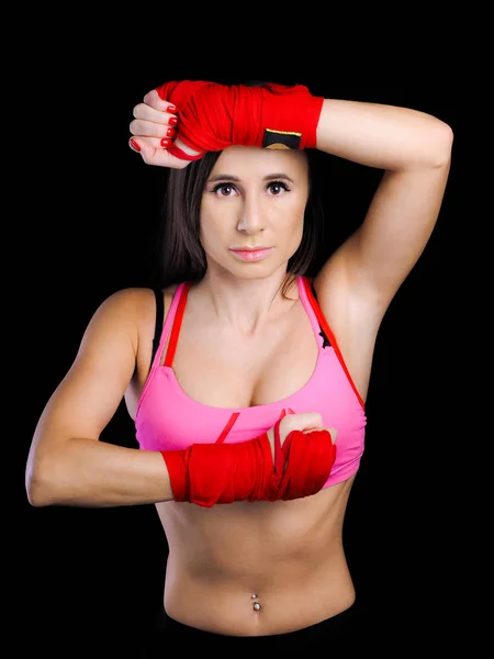 girl in a pink sports bra is engaged in boxing. red bandage glov