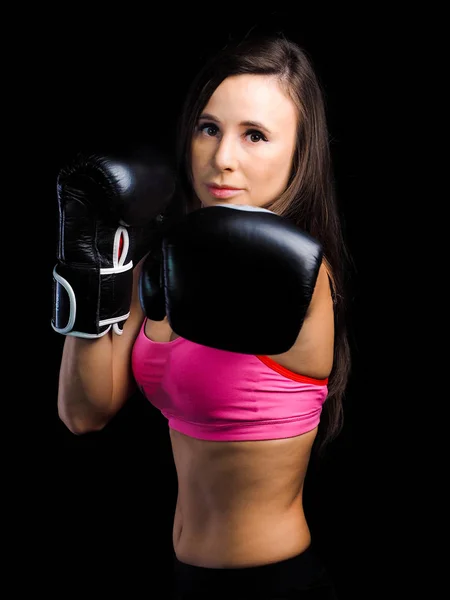 girl in a pink sports bra is engaged in boxing. black gloves for