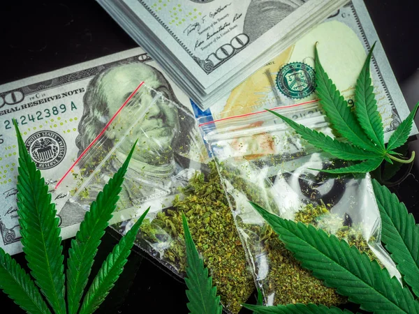 Bags of marijuana and fresh cannabis leaves on a black backgroun — Stock Photo, Image
