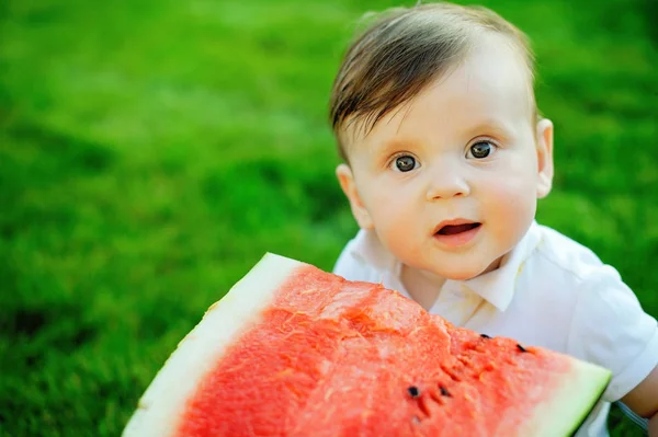 Красивый маленький мальчик ест спелый арбуз на природе — стоковое фото