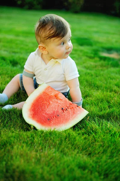 Mooi jongetje eet rijpe watermeloen op de natuur — Stockfoto