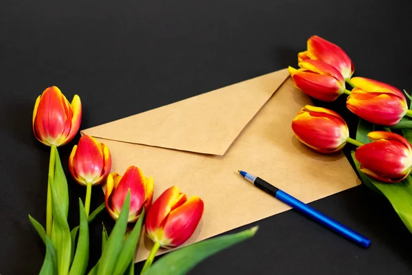 Envelope or letter and tulips on black background for greeting on Mother or Woman Day