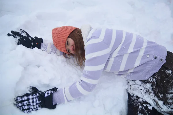 Kar, kar arka plan üzerinde beyaz şapkalı mutlu gülümseyen genç kadın yatıyordu.