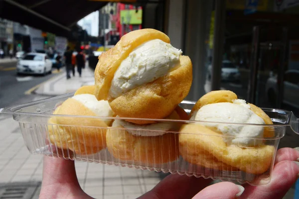 Durian cream puff lub choux krem w ręce kobiety — Zdjęcie stockowe