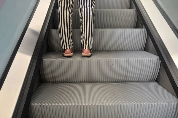 Woman wear sandals step up on an escalator.