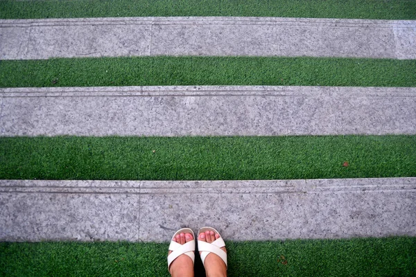 Grünes Gras Treppenstufe mit Frauenfuß auf weißen Schuhen, Backgroun — Stockfoto
