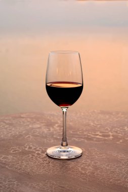 Romantik bir kadeh şarap Renkli gün batımında sahilde ayakta.