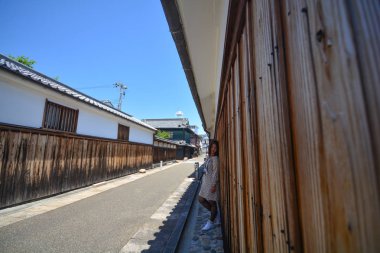 Genç turist kadın bir kamera bakarak eski şehir caddesinde durmak