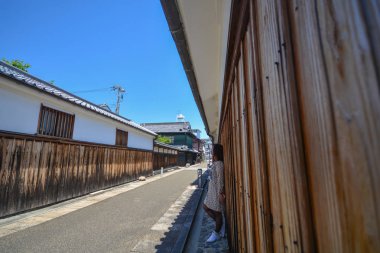 Genç turist kadın bir kamera bakarak eski şehir caddesinde durmak