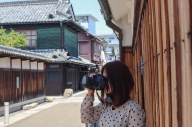 Genç turist kadın bir kamera bakarak eski şehir caddesinde durmak