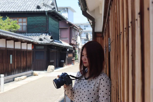 Žena fotografka stojí na ulici na starém městě a dívá se na kameru — Stock fotografie