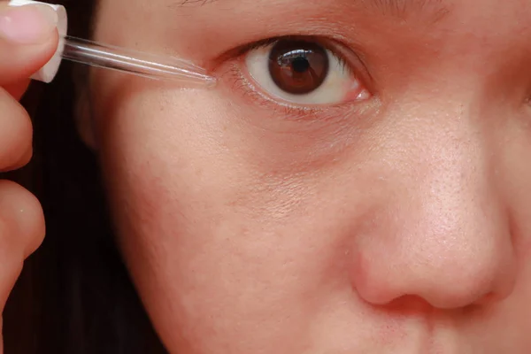 Femme asiatique appliquant un sérum hydratant anti-âge sous les yeux — Photo